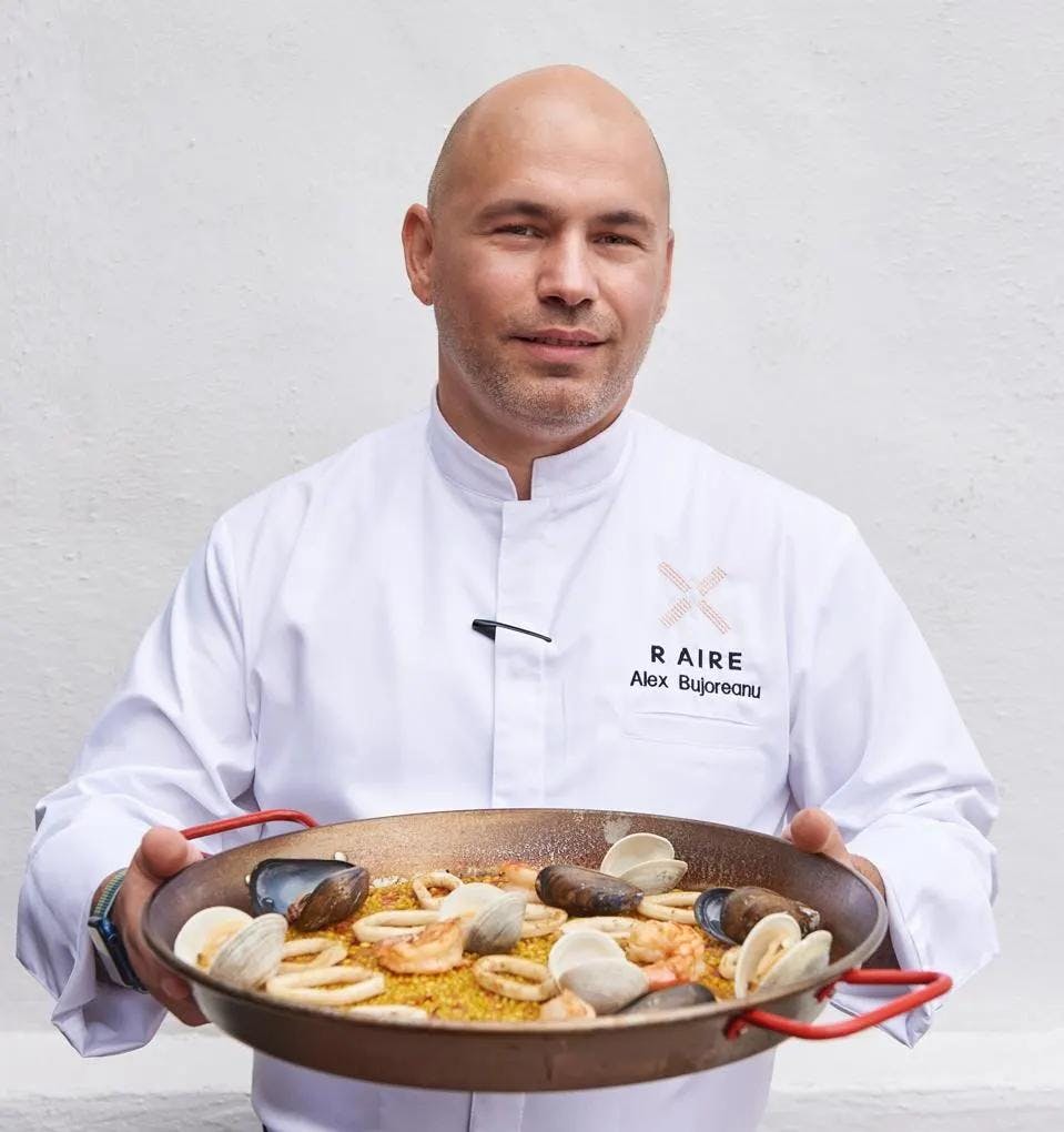 Executive chef of Alex Bujoreanu holding a platter of Paella